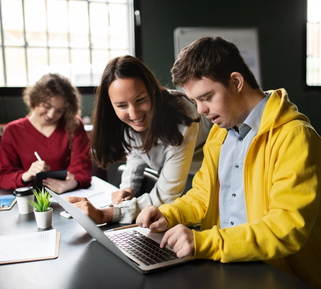 Disabled man using laptop with support worker