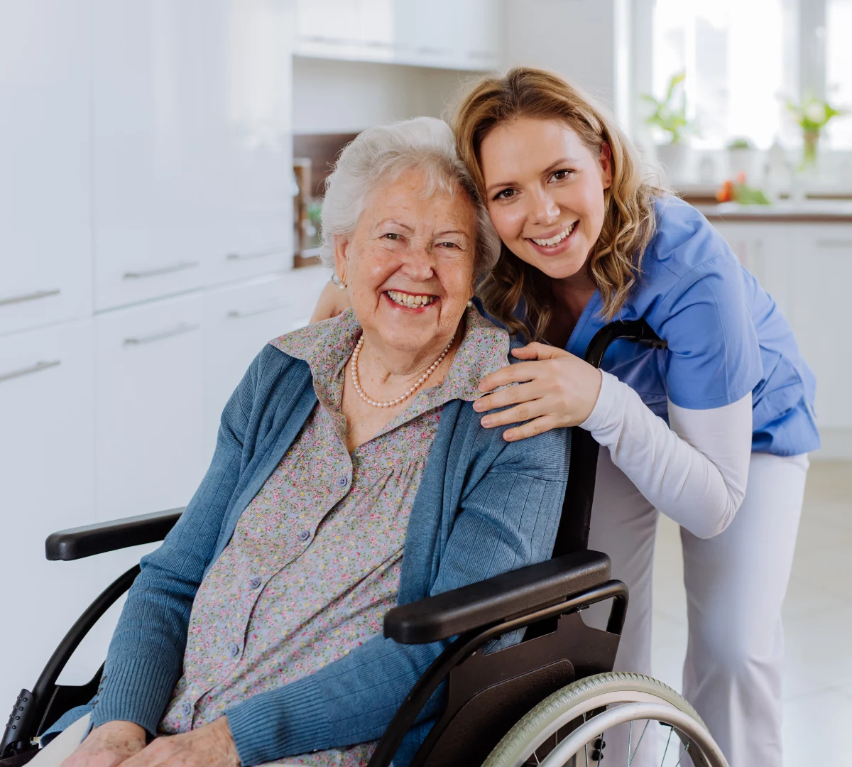 Nurse smiling happily with disabled woman in wheelchair