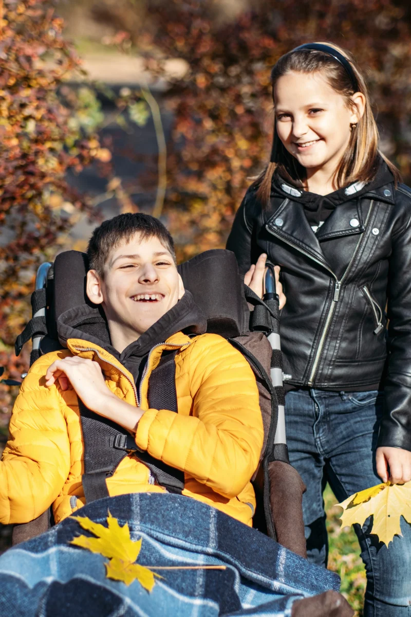 Disabled boy in wheelchair smiling with friend