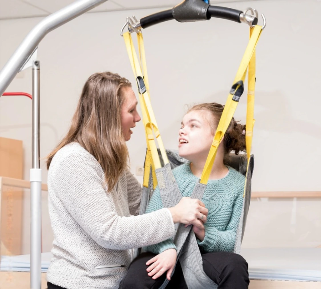Disabled girl in hoist with support worker