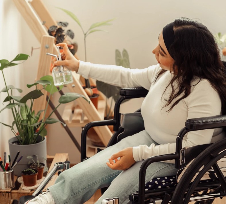 Disabled woman in wheelchair watering plants at home